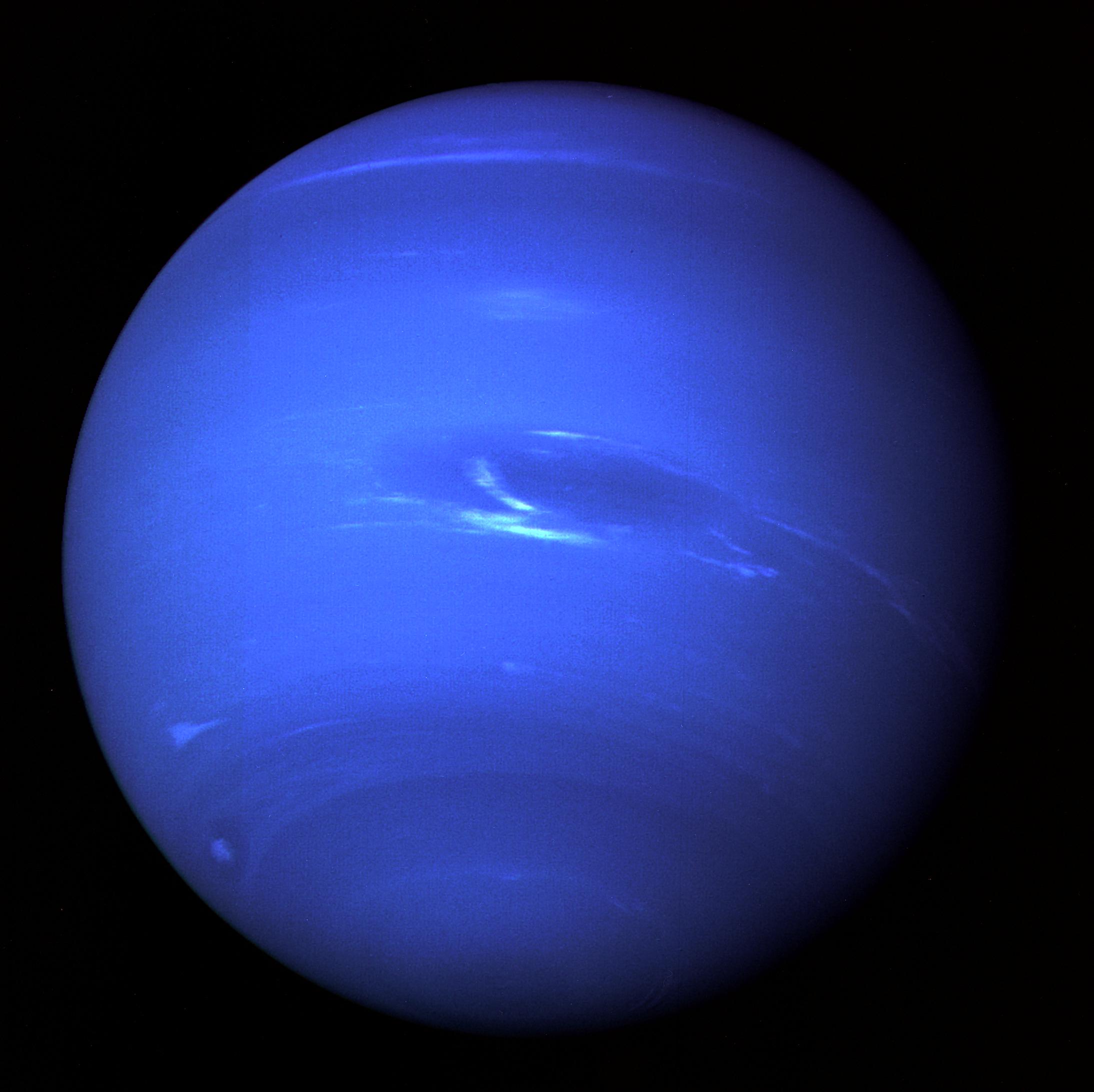 A deep blue planet with wispy white clouds moving across its face.