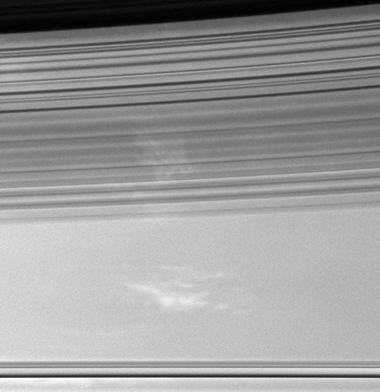 Sweeping shadows of Saturn's C ring cover bright patches of clouds in the planet's atmosphere