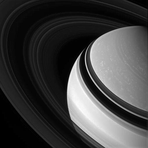 Saturn's darkened, icy rings encircle the clouded gas giant