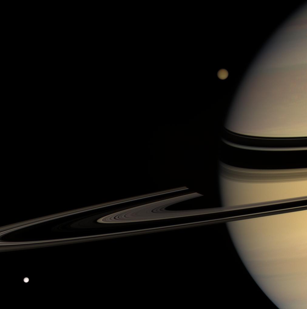 Titan emerges from behind Saturn, while Tethys streaks into view.