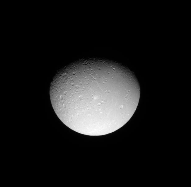 The Cassini spacecraft looks down on the cratered northern leading hemisphere of Dione, showing the moon's pockmarked surface.