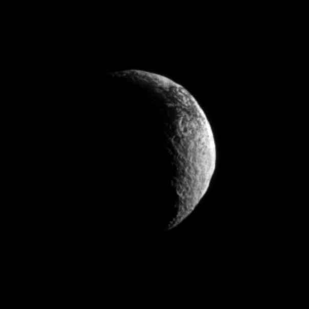 The Cassini spacecraft looks toward a crescent of Saturn's dark and light moon, Iapetus.