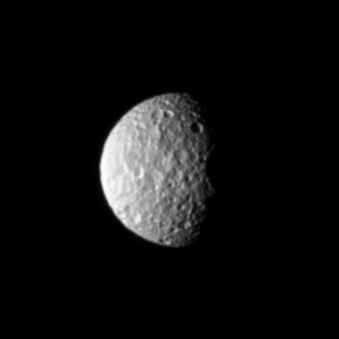 The oblate moon Mimas displays the cratered surface of its anti-Saturn side.