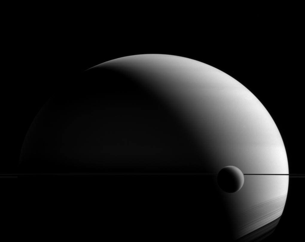 A small crescent shaped orb is shown in front of a larger shadowy grey curved surface.