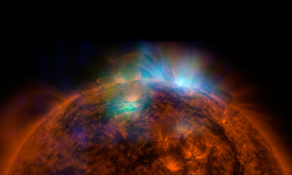 X-rays stream off the sun in this image showing NuSTAR data, seen in green and blue, revealing solar high-energy emission (green shows energies between 2 and 3 kiloelectron volts, and blue shows energies between 3 and 5 kiloelectron volts).