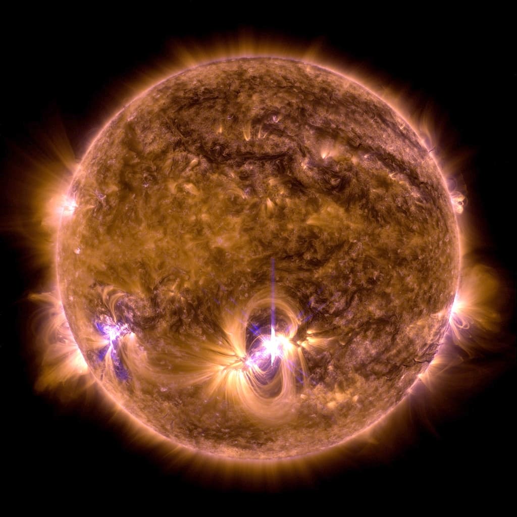 A tannish-orange Sun emits swirling pinkish flares slightly south of the middle of the sphere