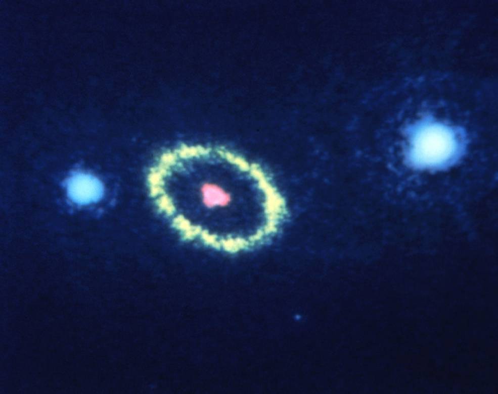 Just left of image center is a pink spot. It is ringed by a yellow-green oval. To its left is a bright-blue spot, another sits to the far right edge.