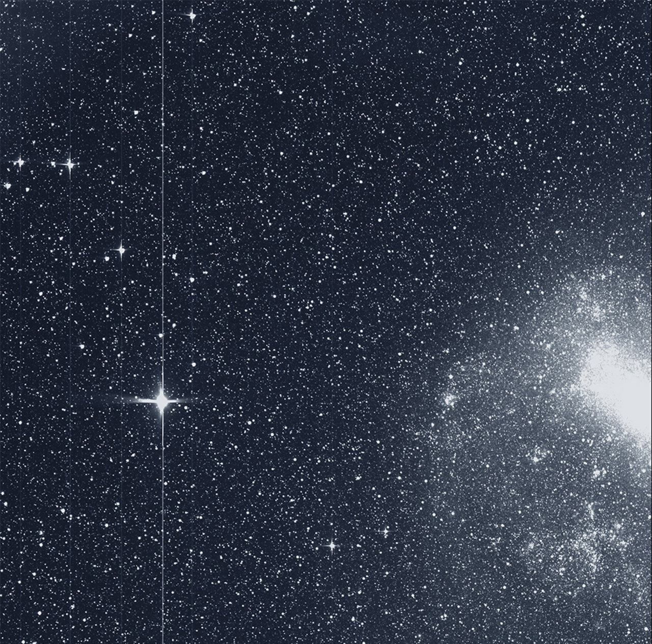 A black and white images showing a bright star in front of a dark sky, with a much brighter cloud.