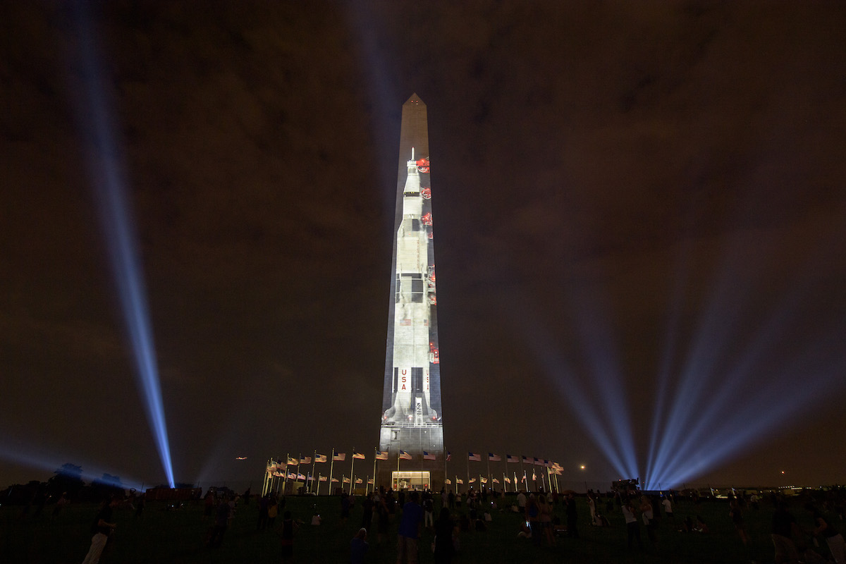 tall monument with rocket image nearly its height appearing on one side