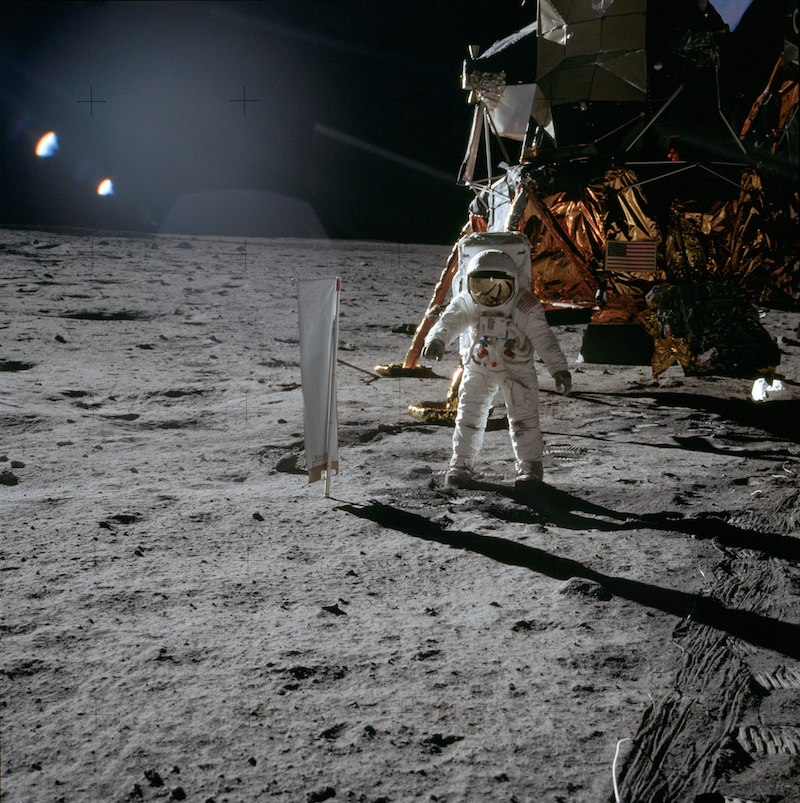 suited astronaut on lunar surface with spacecraft in background