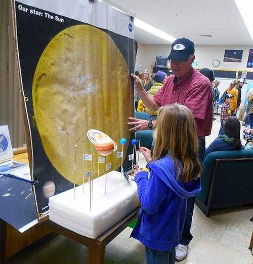 Astronomer showing child a scale model of the solar system