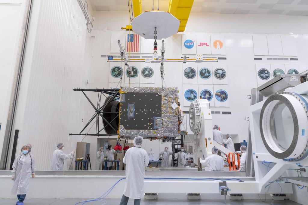 Workers watch as a main component of the Psyche spacecraft is delivered.
