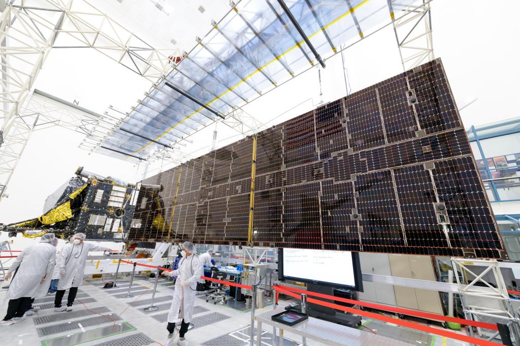 Engineers stand near a large solar panel