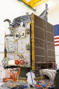 An engineer crouches under the Psyche spacecraft.