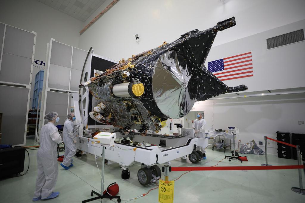 The Psyche spacecraft is on a wheeled transport with workers nearby.