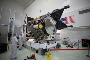 The Psyche spacecraft is on a wheeled transport with workers nearby.