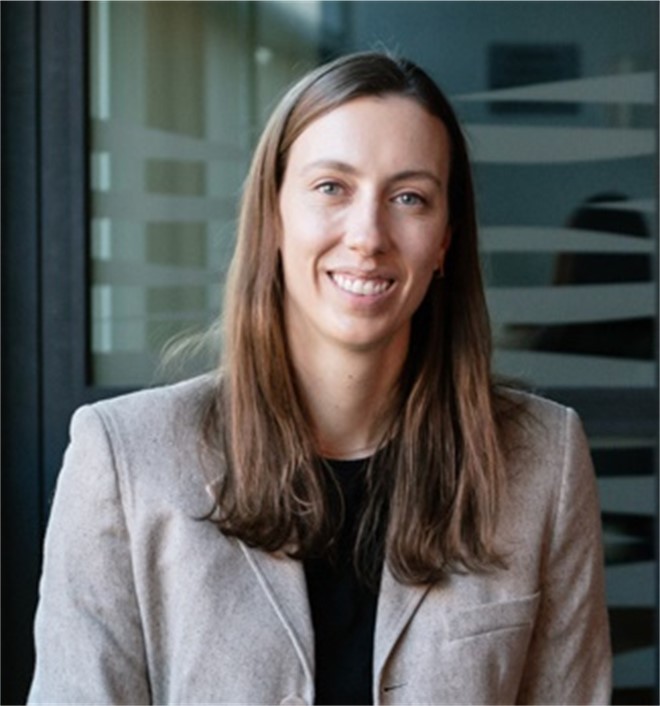 Portrait photo of a person with long hair wearing a blazer over a dark shirt.