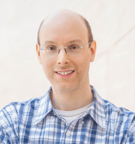 Portrait photo of a person with short hair wearing a plaid collared shirt.