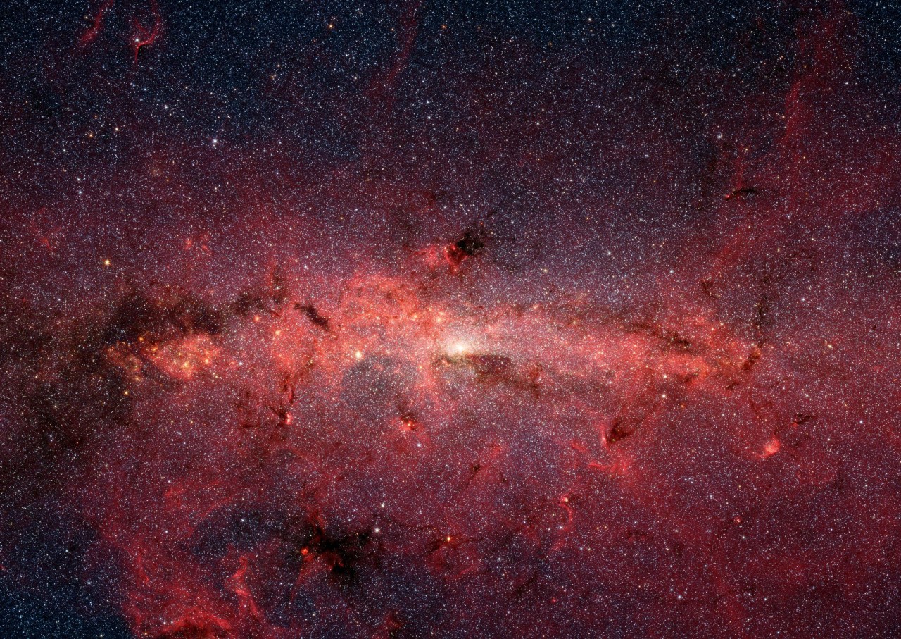 NASA's Spitzer Space Telescope's infrared cameras penetrate much of the dust, revealing the stars of the crowded galactic center region.