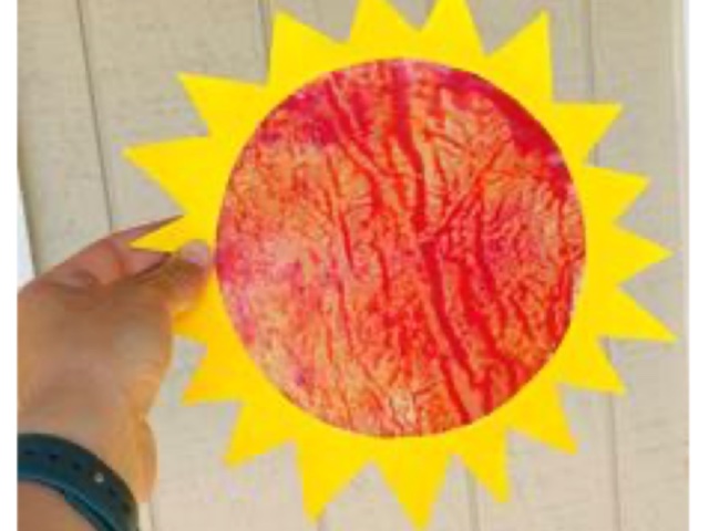 An hand holding an artistic creation of the Sun.