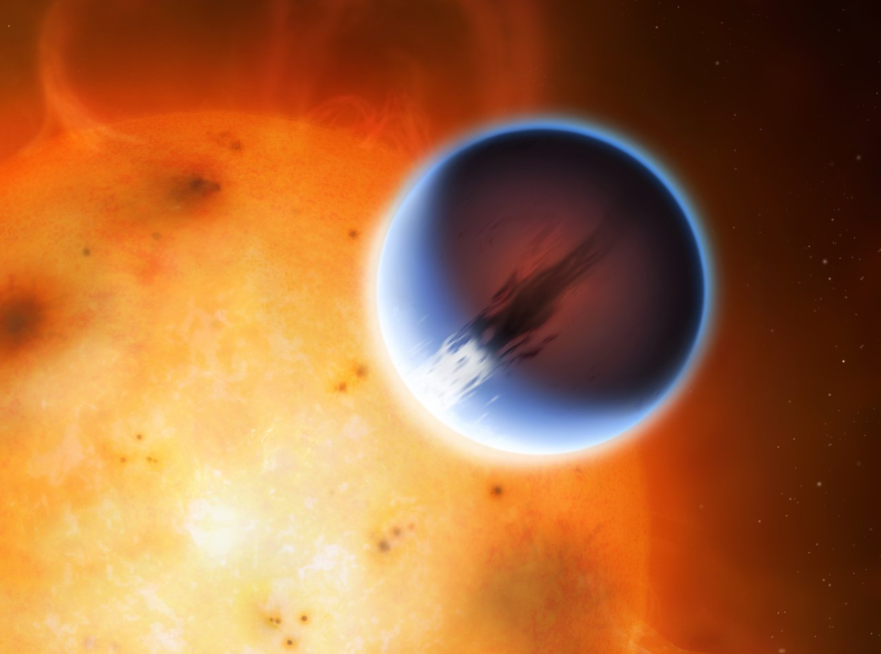 The planet HD 189733 b is shown here in front of its parent star. A belt of wind around the equator of the planet travels at 5400mph from the heated day side to the night side. The day side of the planet appears blue due to scattering of light from silicate haze in the atmosphere. The night side of the planet glows a deep red due to its high temperature. Image credit: Mark A. Garlick/University of Warwick