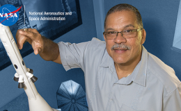 Photo of man pointing to model spacecraft