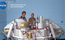 Photo of two men standing behind the Viking Lander spacecraft