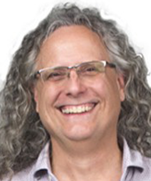 Photo of person smiling with glasses and long grey curly hair