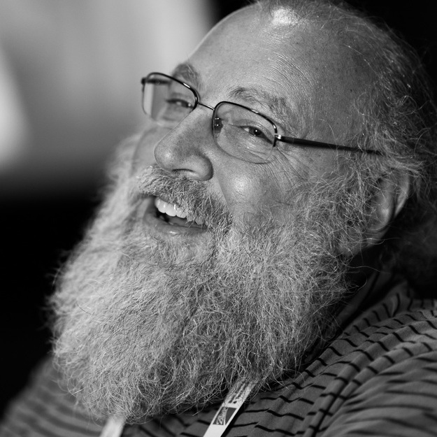 man with beard and glasses smiles off camera to the left