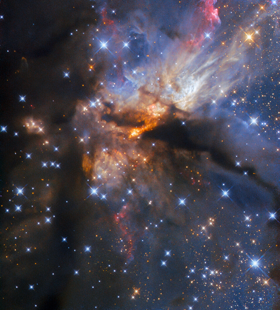 A nebula with stars. Dense clouds of dust and gas cover the left-hand side and a filament crosses the center horizontally. Billowing streams of gas and dust in various colors emerge from around the center. The very center of the image is permeated with glowing orange regions. Many blue stars with cross-shaped spikes lie in the foreground, and small point-like stars are visible beyond the clouds.