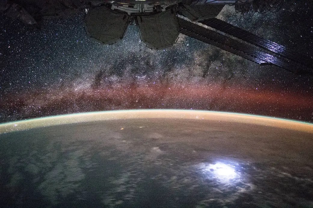 An image of the curve of the Earth taken from the International Space Station. a faint red glow of gas -- airglow -- rest above the horizon against a starry sky.