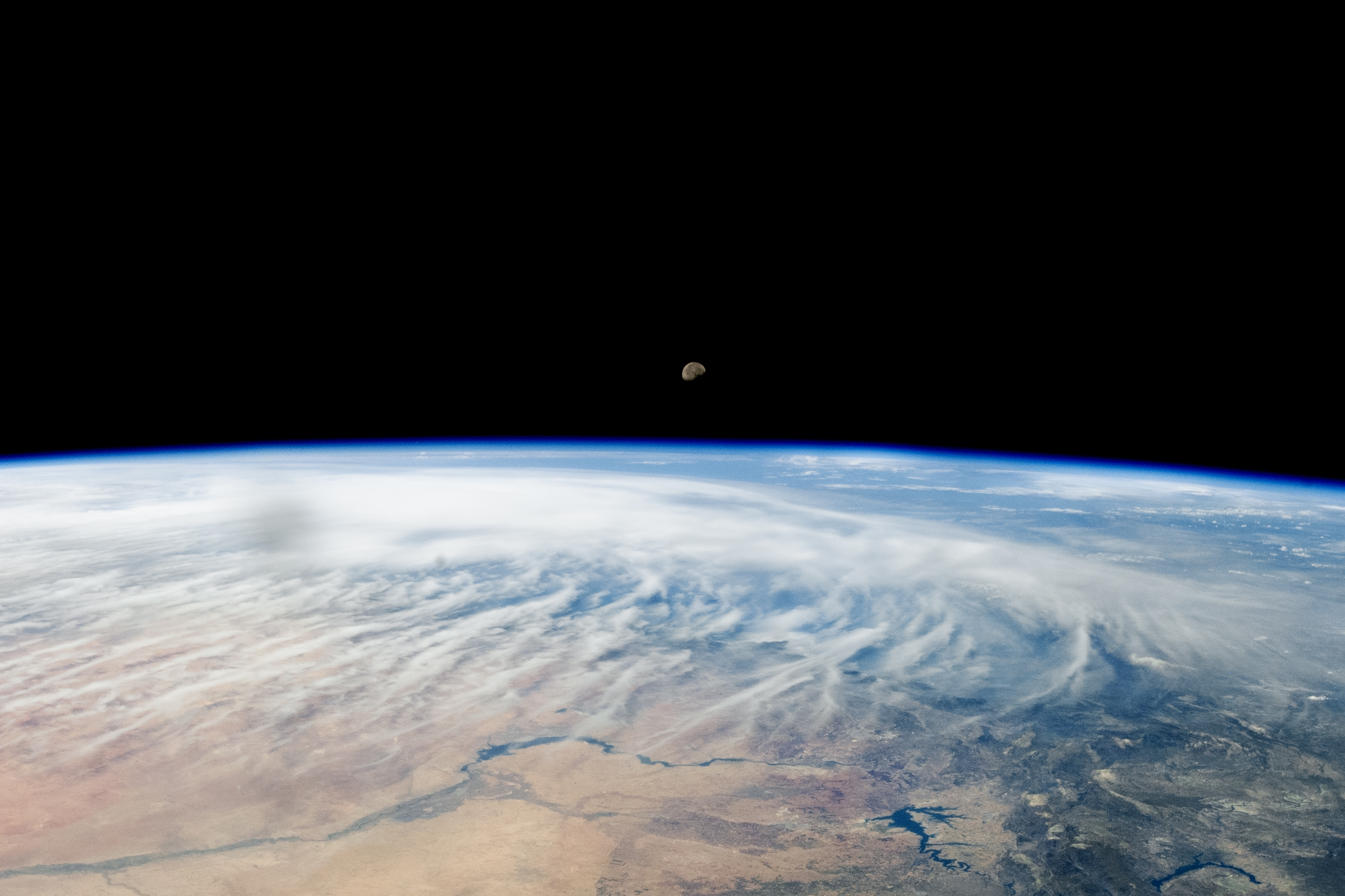 An oblique-angle photo taken from above the Middle East captures the Moon peeking over Earth’s atmospheric limb.