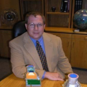 man in a tan suit sitting at a table