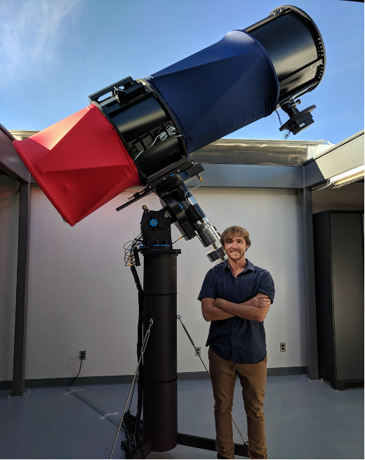 Photo of a man standing underneath a telescope