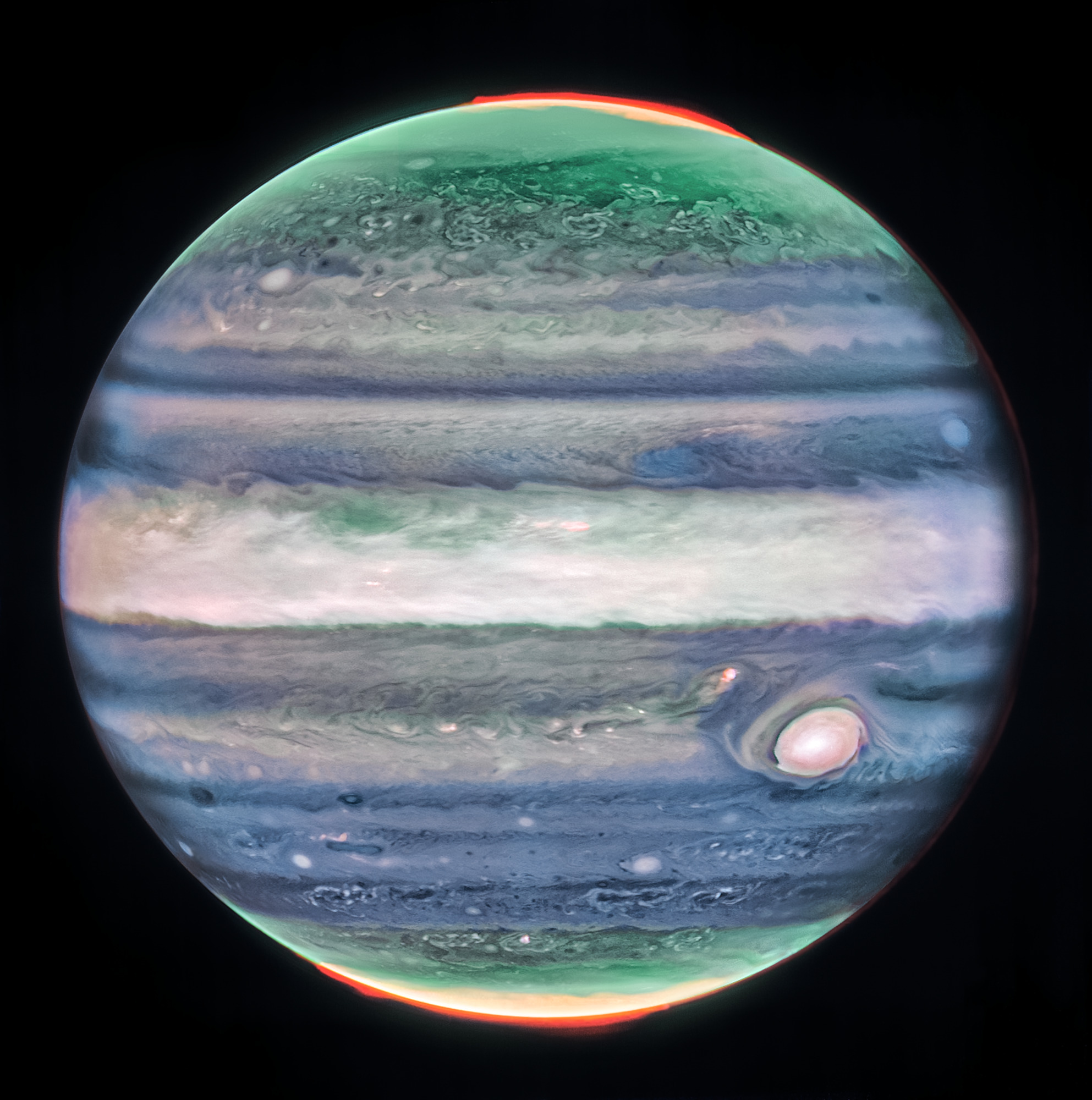 Jupiter dominates the black background of space. The image is a composite, and shows Jupiter in enhanced color, featuring the planet’s famous Great Red Spot, which appears white with light pink around the edges. The planet is striated with swirling horizontal stripes of green, periwinkle, light pink, and cream. Horizontally across the equator is a wide cream-colored band, whose height extends about 1/7 of the planet. This is the planet’s equatorial zone. The stripes across the planet interact and mix at their edges. Along both of the northern and southern poles, the planet glows in green. Bright red auroras glow just above the planet’s surface at both poles.