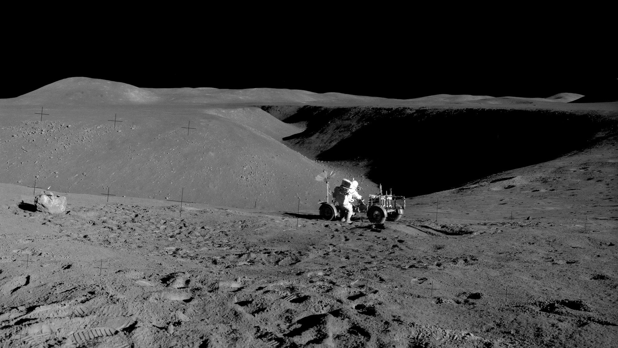 An astronaut works near a Moon buggy on the surface of the Moon.