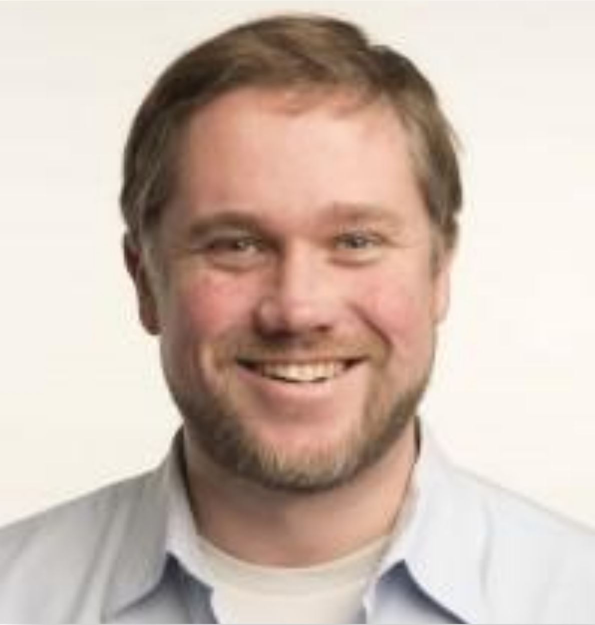 Headshot of Nathan Lundblad smiling in a light gray button-up shirt.