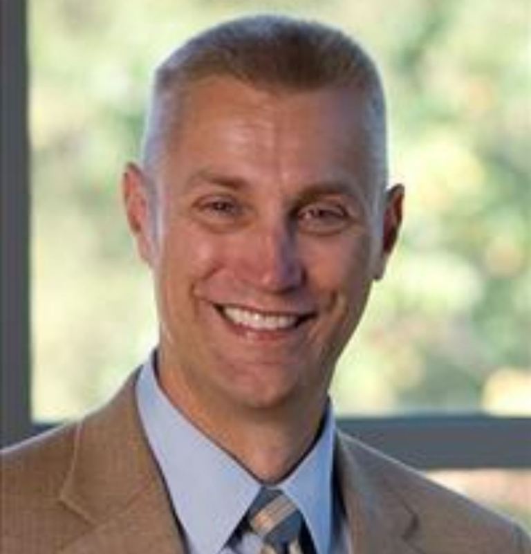 Headshot of James Pawelczyk smiling in a suit and tie.