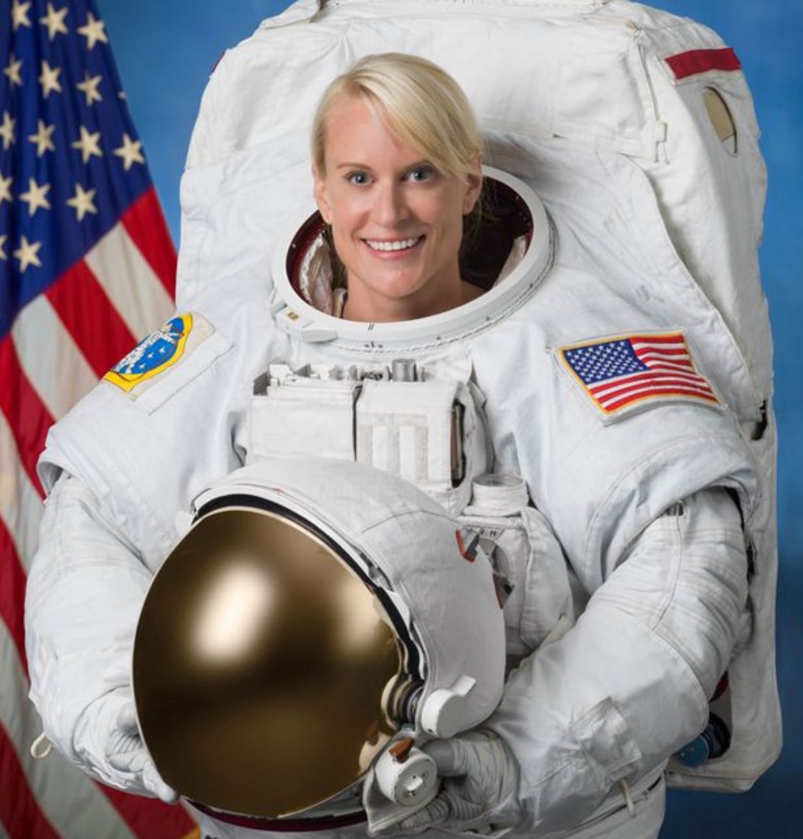 Portrait of Dr. Kathleen (Kate) Rubins in a spacesuit holding a helmet.