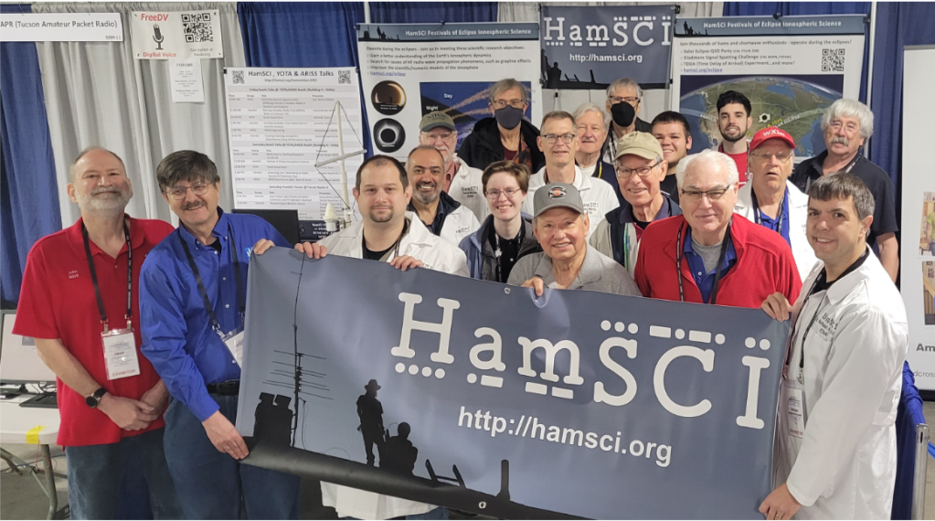 Group photo of 17 people standing together and those in front holding a banner that reads "HamSci"