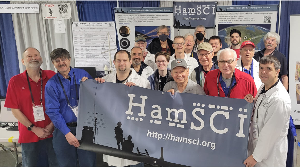 Group photo of 17 people standing together and those in front holding a banner that reads "HamSci"
