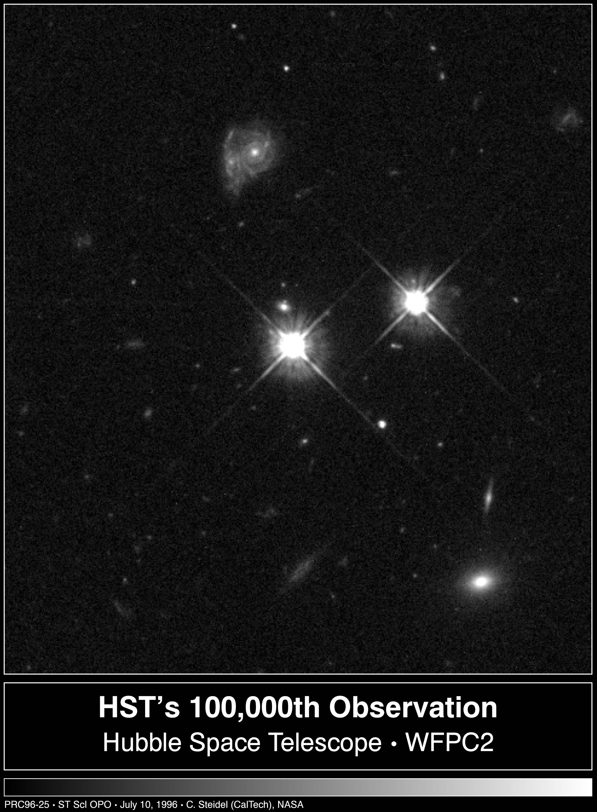 Black and white image. Two bright points of light, one at image center, the other slightly above and to the right. Top center of the image holds 2 galaxies together, at least one is a spiral.