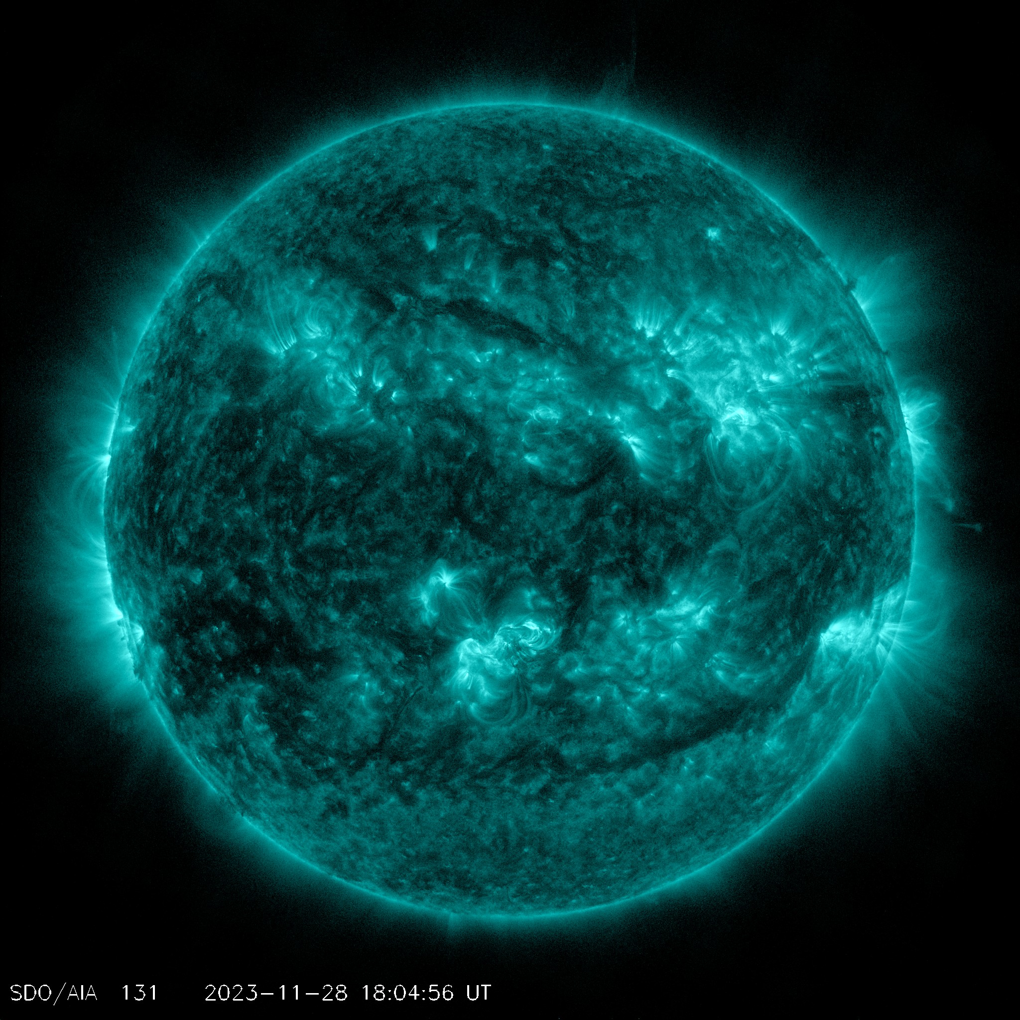 An aqua-colorized satellite image of the sun with solar flares