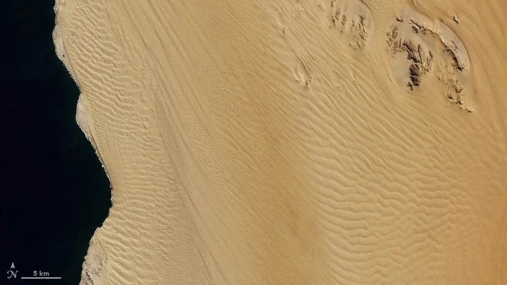 Satellite view of golden-colored sand dunes.