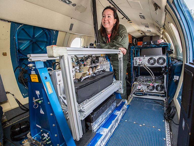 Laura Judd, postdoctoral researcher at NASA Langley, prepares for a LISTOS science flight on the center's HU-25 aircraft. GeoTASO, a remote-sensing instrument that observes reflected sunlight to measure atmospheric trace gases and aerosols over a wide area, is visible in the foreground.