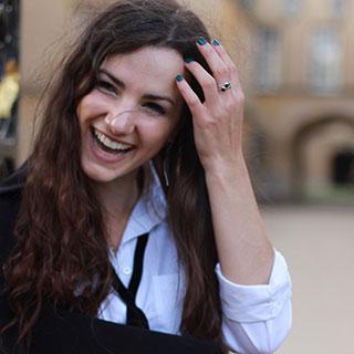 Portrait photo of smiling young woman with her hand pushing her long dark hair out of her face