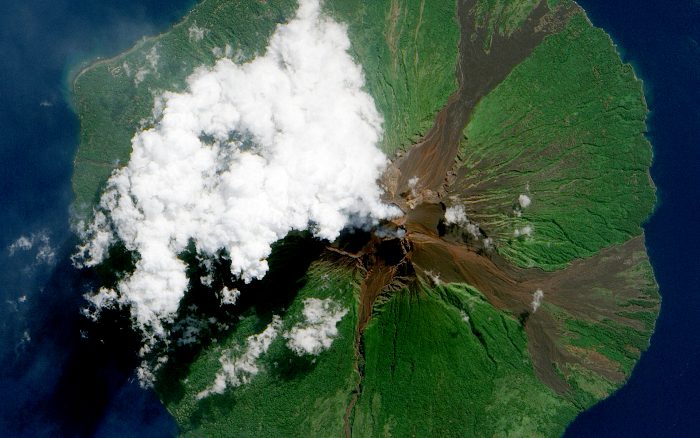 MANAM VOLCANO: Manam Volcano in Papua New Guinea, as seen from space on June 16, 2010. Located 13 kilometers (8 miles) off the coast of mainland Papua New Guinea, Manam forms an island 10 kilometers (6 miles) wide. It is a stratovolcano. The volcano has two summit craters, and although both are active, most historical eruptions have arisen from the southern crater.On June 16, the volcano released a thin, faint plume as clouds clustered at the volcano's summit. Rivulets of brown rock interrupt the carpet of green vegetation on the volcano’s slopes. White clouds partially obscure the satellite’s view of Manam. The clouds may be the result of water vapor from the volcano, but they may also have formed independently of volcanic activity. The volcanic plume appears as a thin blue-gray veil extending toward the northwest over the Bismarck Sea.