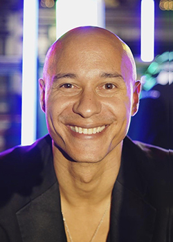 Portrait photo of a smiling bald man in a dark shirt.