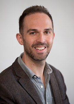 Portrait photo of a smiling bearded man.