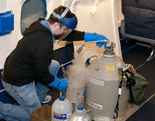 On board the DC-8 aircraft, Justin Trice of Exelis Inc. readies liquid nitrogen that will be used to cool part of the Multi-functional Fiber Laser Lidar, or MFLL, a system that uses laser light to measure atmospheric carbon dioxide.Credit: NASA/Tom Tschida